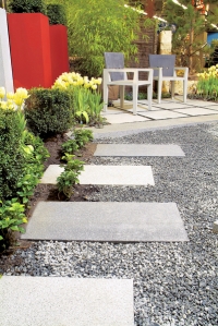 Betonové dlaždice použité jako šlapáky mezi zelení a kameny (ZAHRADA PRAHA).
