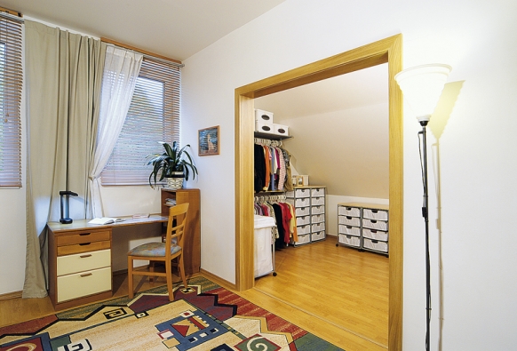 Na ložnici rodičů navazuje prostorná šatna pod zkoseným stropem, vybavená praktickými doplňky z IKEA.