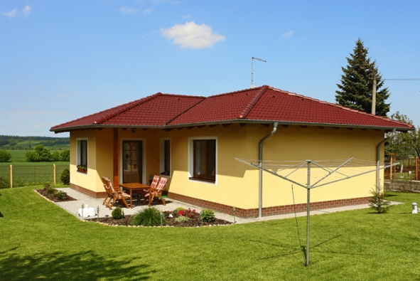 Konečný vzhled domu výrazně určuje barevnost fasády v kombinaci s betonovou střešní krytinou Bramac. V tomto případě dům „oblékla“ okrově probarvená omítka s kontrastním bílým olemováním oken a vstupních dveří, doplněná pásem obkladových pásků, chránících fasádu po celém obvodu v nejnamáhanější části těsně nad zemí.