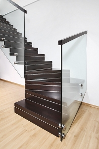 HARMONY – třmenové schodiště kombinující moderní nerez, sklo a masivní dřevo. Decentní kovové proužky na jednotlivých stupních elegantně dolaďují celkový vzhled (J.A.P.)