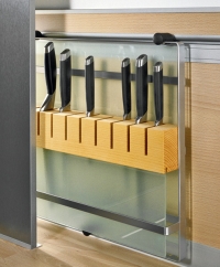 Držák nožů v kombinaci nerezu, skla a dřeva lze posouvat po zadní stěně mezi spodními a horními skřínkami. Posouvání v hliníkové drážce obložení zajišťují plastové kluzáky. Dodává se jako součást ALNO systému zadního obložení, nelze používat samostatně (INTERIÉR ČÁP)