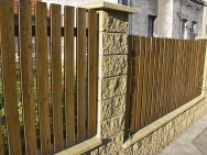 Zděná konstrukce obložená štípaným betonem s plotovými výplněmi ze dřeva.