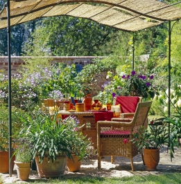 Středomořské rostliny v květináčích, proutěný zahradní nábytek a pergola promění hodiny na zahradě v malou dovolenou.