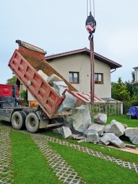 Doprava velkých a hmotných materiálů na zahradu vypadá dramaticky, ale když se vše pohlídá, není to velký problém. Na obrázku Tatra vysypává žulové balvany na trávník a plastové zatravňovací rošty. Pokud pod kameny položíte alespoň nějaké desky a trámky, obejde se i taková akce bez větších škod. Počítejte ale s tím, že auto váží 10 tun a náklad dalších 10–15 tun. Díky velkému počtu kol se váha dobře rozloží, podmínkou je však suché počasí.