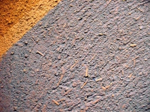 Hliněná omítka s příměsí částeček slámy natřená přírodním pigmentem.