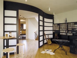 Dřevěná příčka obývací místnosti s výplní z mléčného skla má tvar vlnovky.