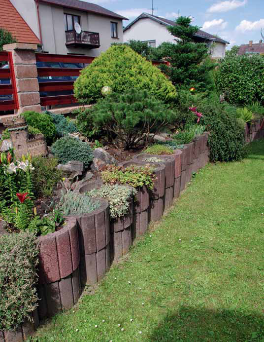 V přední, níže položené části zahrady je pomocí betonových tvarovek vybudována terasa, díky níž jsou záhony v úrovni chodníku.