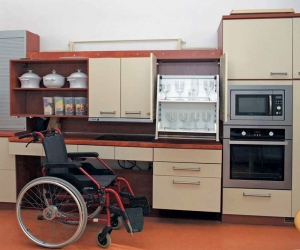 Kuchyňská sestava slouží v pražské Klinice rehabilitačního lékařství k nácviku soběstačnosti. Horní nábytkový díl i pracovní deska jsou výškově nastavitelné, horní police jsou vybavené sklápěcí konstrukcí. Individuální nastavení výšky umožňuje i deska se zabudovaným dřezem.