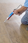 K vyplnění veškerých pružných spojů, dilatačních spár a míst styku podlahy se soklem se hodí silikonový nebo polyuretanový tmel.