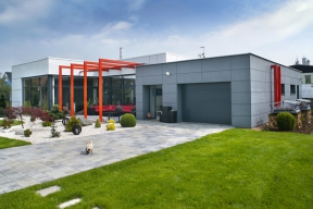 Kompozice domu je rozdělena na nižší hmotu garáže, obloženou cembonitem, a obytnou část s vyšším stropem a obložením fasády z kompozitních panelů Alubond s hliníkovým pláštěm.