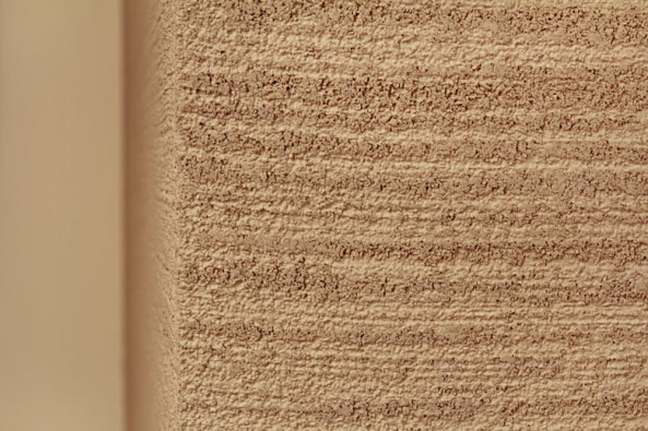 Hlazená omítka Travertine propůjčí stěně bytu porézní vrásnitou strukturu i barevnost charakteristickou pro přírodní kámen travertin (Luxusní povrchy Němec).