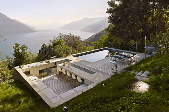 Terasa s venkovní kuchyní a bazénem je obklopena z jedné strany zelení a z druhé velkolepým prostorem zakončeným siluetou Alp.