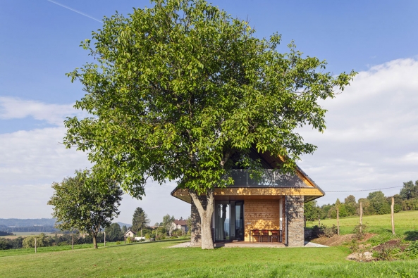 „Dům za vesnicí, kde stála malá chalupa. Za lípou a před kaštanem, s výhledem daleko do kraje.“ Tak charakterizují architekti z ateliéru ov-a stavbu určenou k dlouhodobé relaxaci čtyřčlenné rodiny a pokračují: „Nový dům převzal tvarosloví stodol uprostřed luk. Mezi kamennými pilíři jsou sevřené prostory zázemí, v otevřených polích volnost. A střecha s konstrukcí čistého trojúhelníku.“ Co dodat?