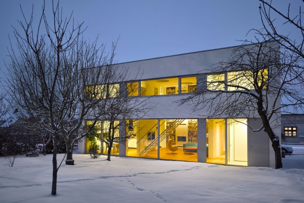 Zimní atmosféra ještě zvýrazňuje střízlivou estetiku domu, založenou na principech  funkcionalistické architektury: elementární geometrické tvary, pásové prosklené plochy,  hladké bílé fasády, žádné zbytečné prvky...