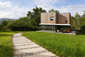 Architektonický koncept domu využívá kontrast lehkého, bohatě proskleného přízemí a kompaktního horního podlaží s modřínovým obkladem a několika menšími komponovanými okny