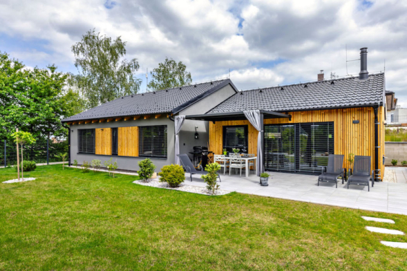 Dům o velikosti 110,4 m2 užitné plochy o dispozici 3 + kk má zajímavě kombinovanou fasádu z šedé omítky a dřevěného obkladu ze sibiřského modřínu