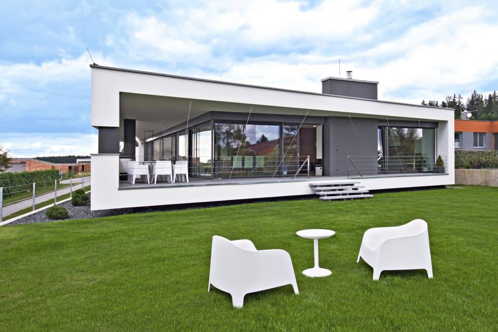 Přízemní dům ve svahu s plochou střechou a bílým rámem fasády