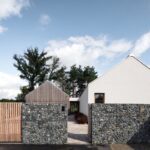 Dům je rozdělen do dvou částí, které propojuje otevřený krček sloužící zároveň jako rozhraní mezi obytnou zónou a garáží s kadeřnickým salonem. Hlavní obytný prostor s kuchyní je otevřený až do krovu