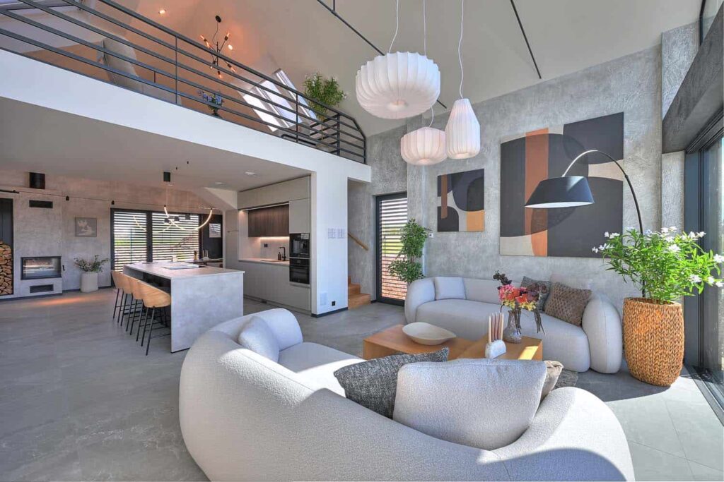 Design interiéru navrhlo studio Momenti Design. Hlavní obývací prostor má na stěnách šedou stěrku a na podlaze velkoformátovou dlažbu, neutrální základ doplňuje dřevo a prvky z černého kovu. Za kuchyňskou linkou se skrývá schodiště na galerii