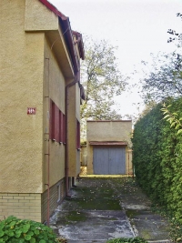Hlavní vstup do domu je umístěn vzadu vedle garáže.