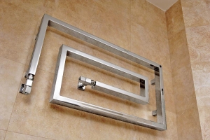 Designový otopný žebřík z nerezové oceli má tvar stočeného hada.