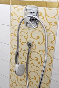 Podomítková sprchová baterie se dobře vyjímá na obkladu s ornamentálním zlatým dekorem.