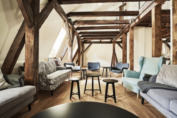 Zrekonstruované podkroví je vybaveno nábytkem v retro stylu a slouží k relaxaci. Historický krov architekti zkombinovali s moderními konstrukčními prvky ze skla a oceli.