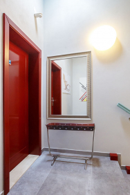 Vstupní chodba do apartmánu UP vybavená dobovými solitérními doplňky – zrcadlem a úzkým trubkovým odkládacím stolkem.